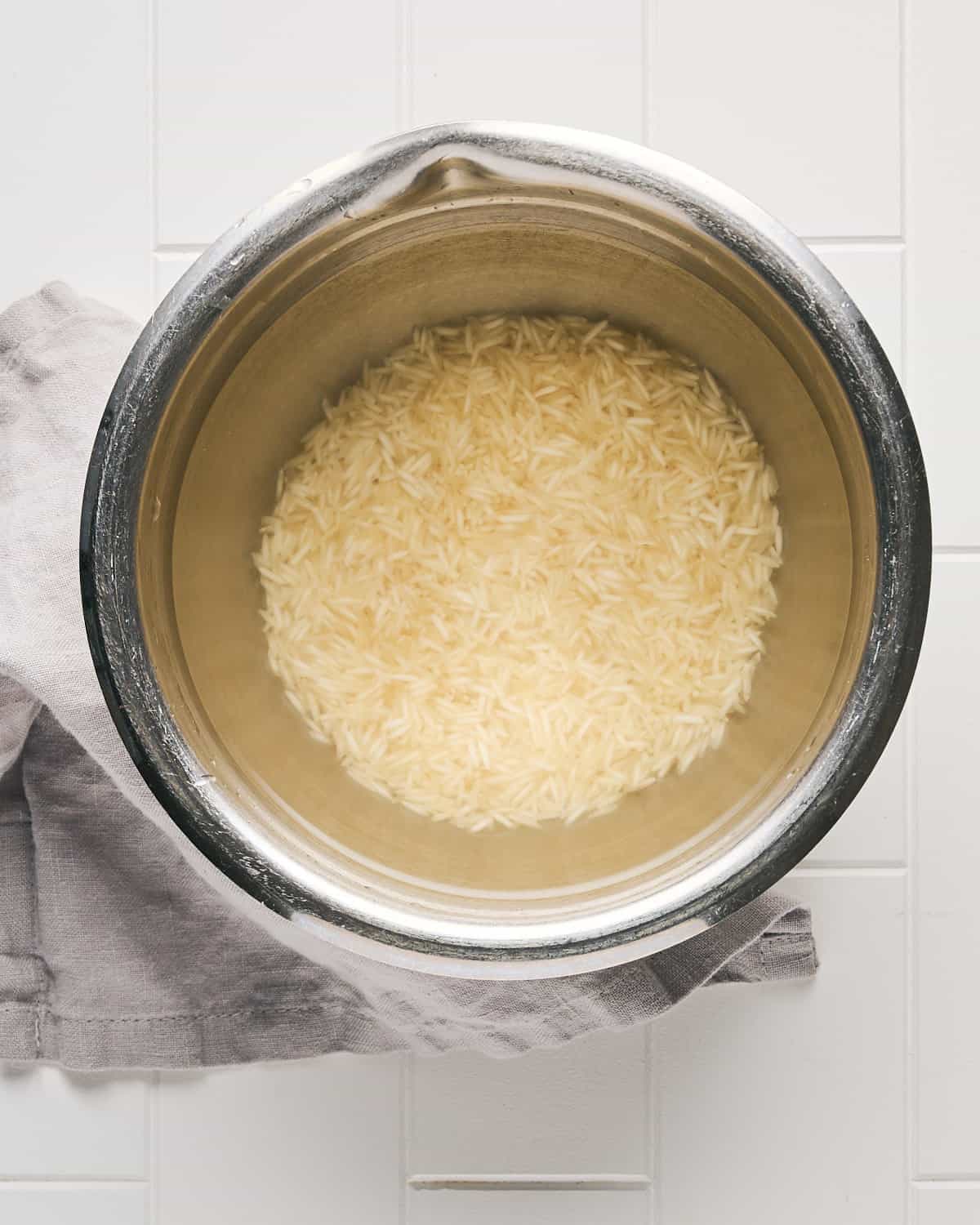 Overhead view of Long Grain White Rice covered with water for rinsing in a Bowl.