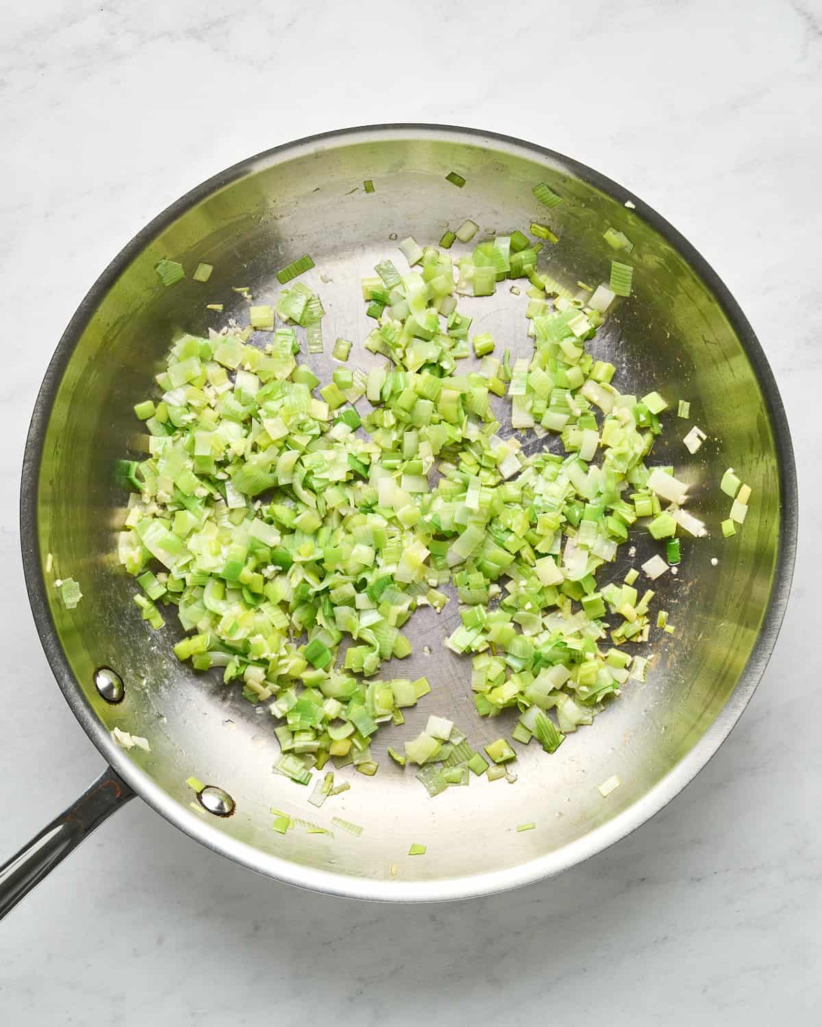 Cooking leeks in a large skillet for JUST Egg Frittata recipe.
