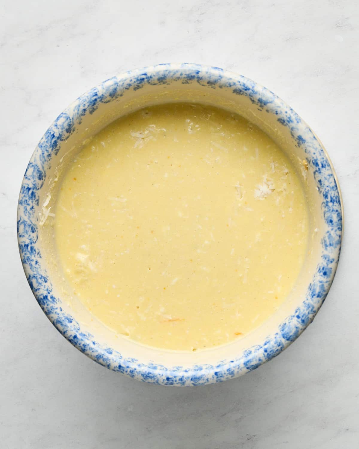 JUST Egg Frittata batter in a blue and white mixing bowl on a marble surface.