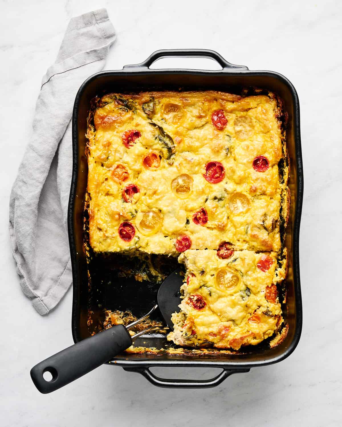JUST Egg Frittata in a baking dish with a portion taken out with a spatula.