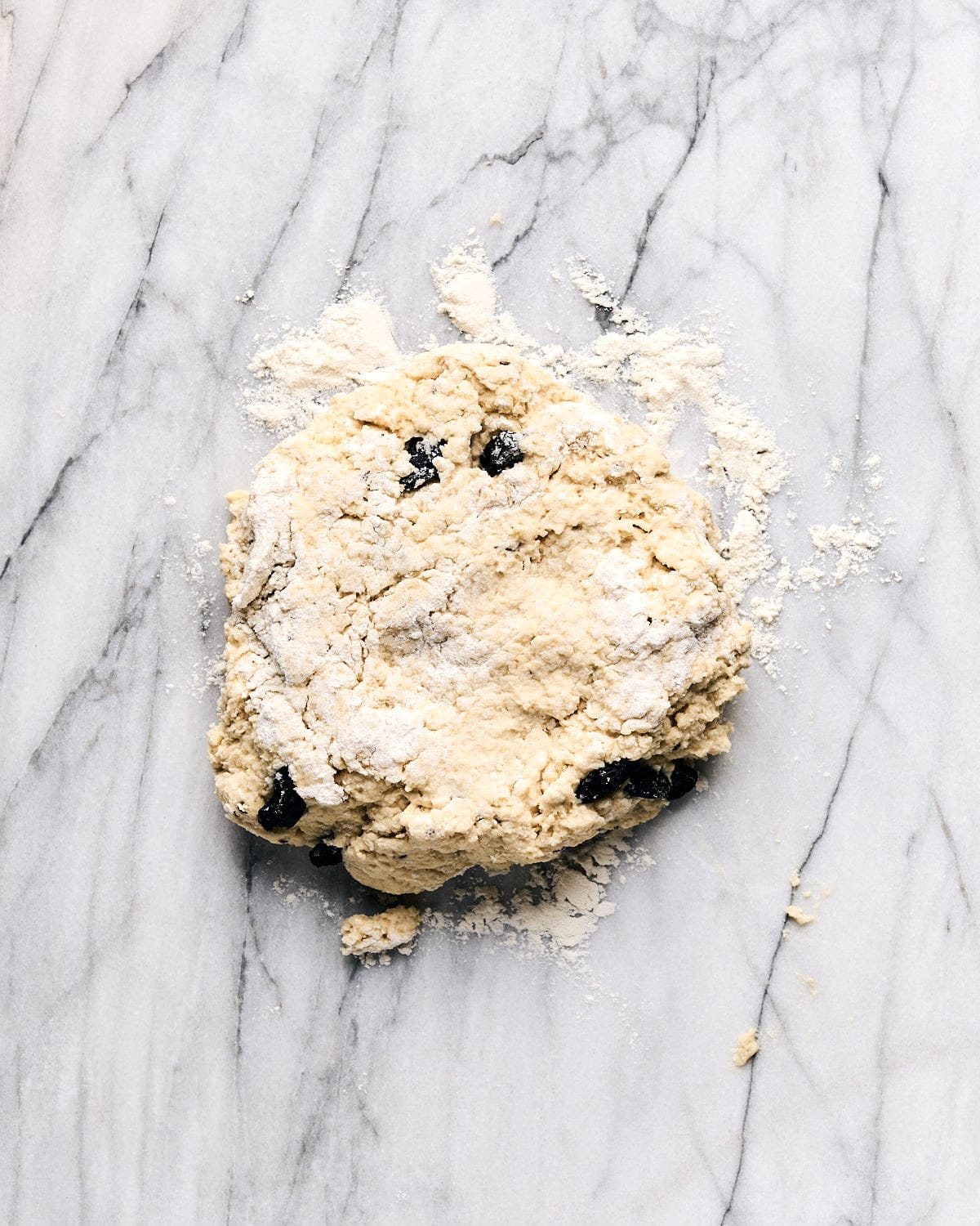 Dough on a floured marble counter pressed into a loose round.