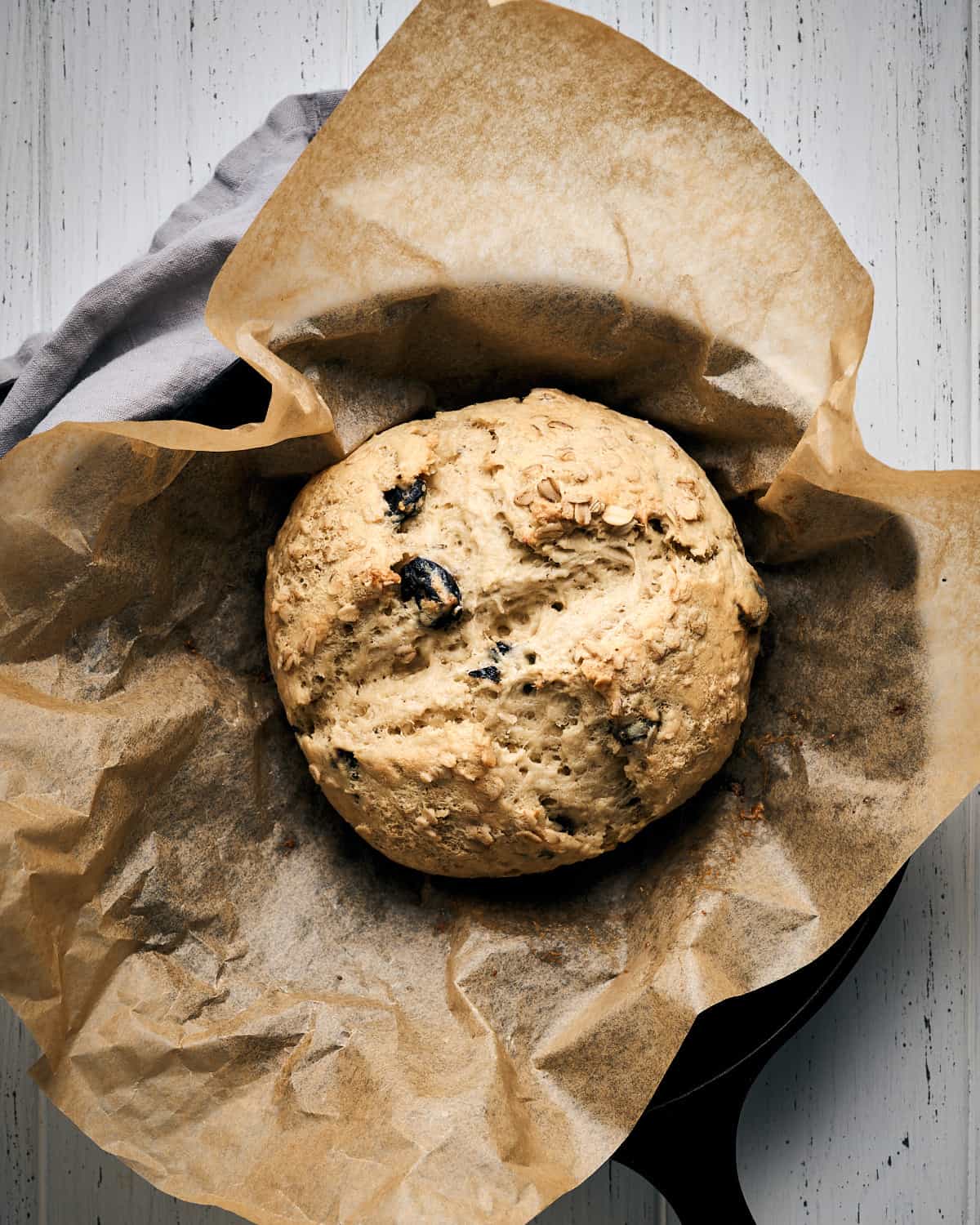 Baked Vegan Irish Soda Bread on parchment paper in a cast iron skillet.