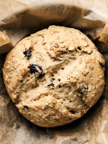 Baked Vegan Irish Soda Bread on parchment paper in a cast iron skillet.