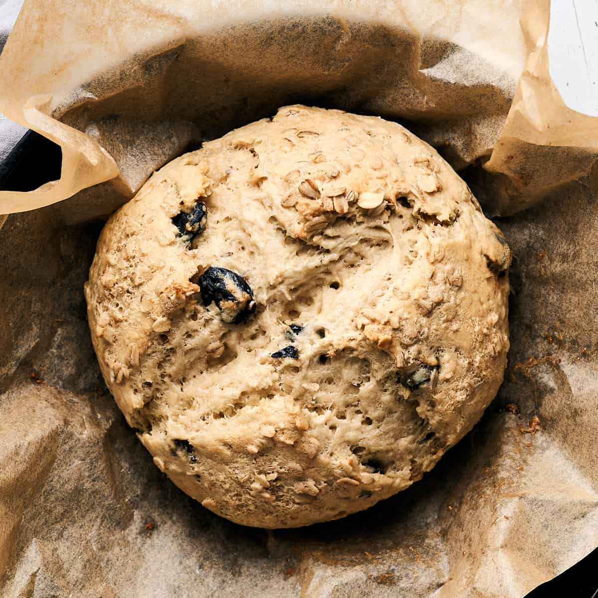 Baked Vegan Irish Soda Bread on parchment paper in a cast iron skillet.