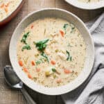 A bowl of vegan gnocchi soup with a napkin and spoons nearby.