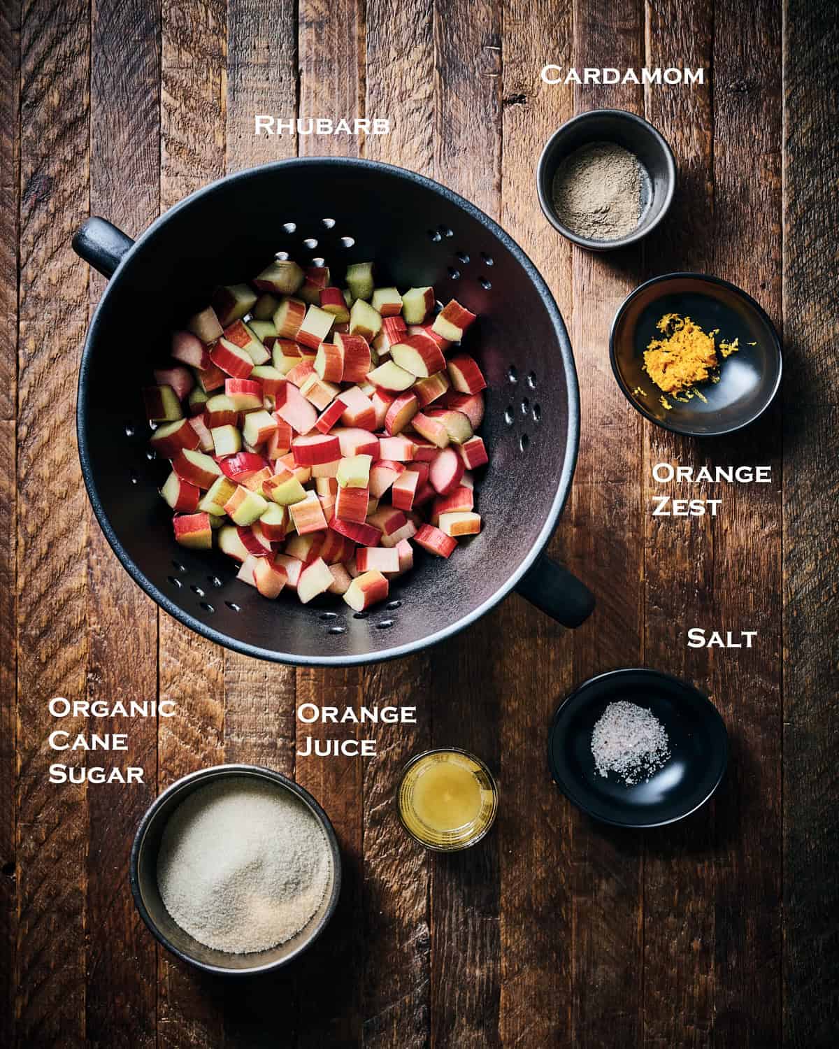 Ingredients ready to make fresh rhubarb compote on a wood surface.