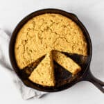 Vegan southwest skillet cornbread in cast iron skillet on marble surface with grey napkin.