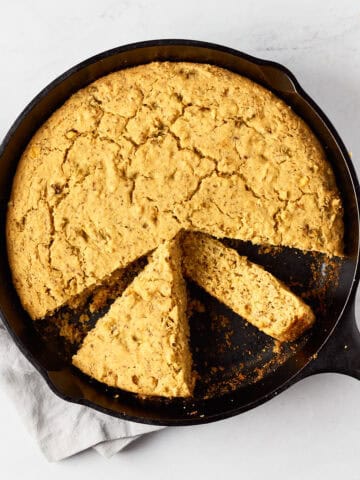 Vegan southwest skillet cornbread in cast iron skillet on marble surface with grey napkin.