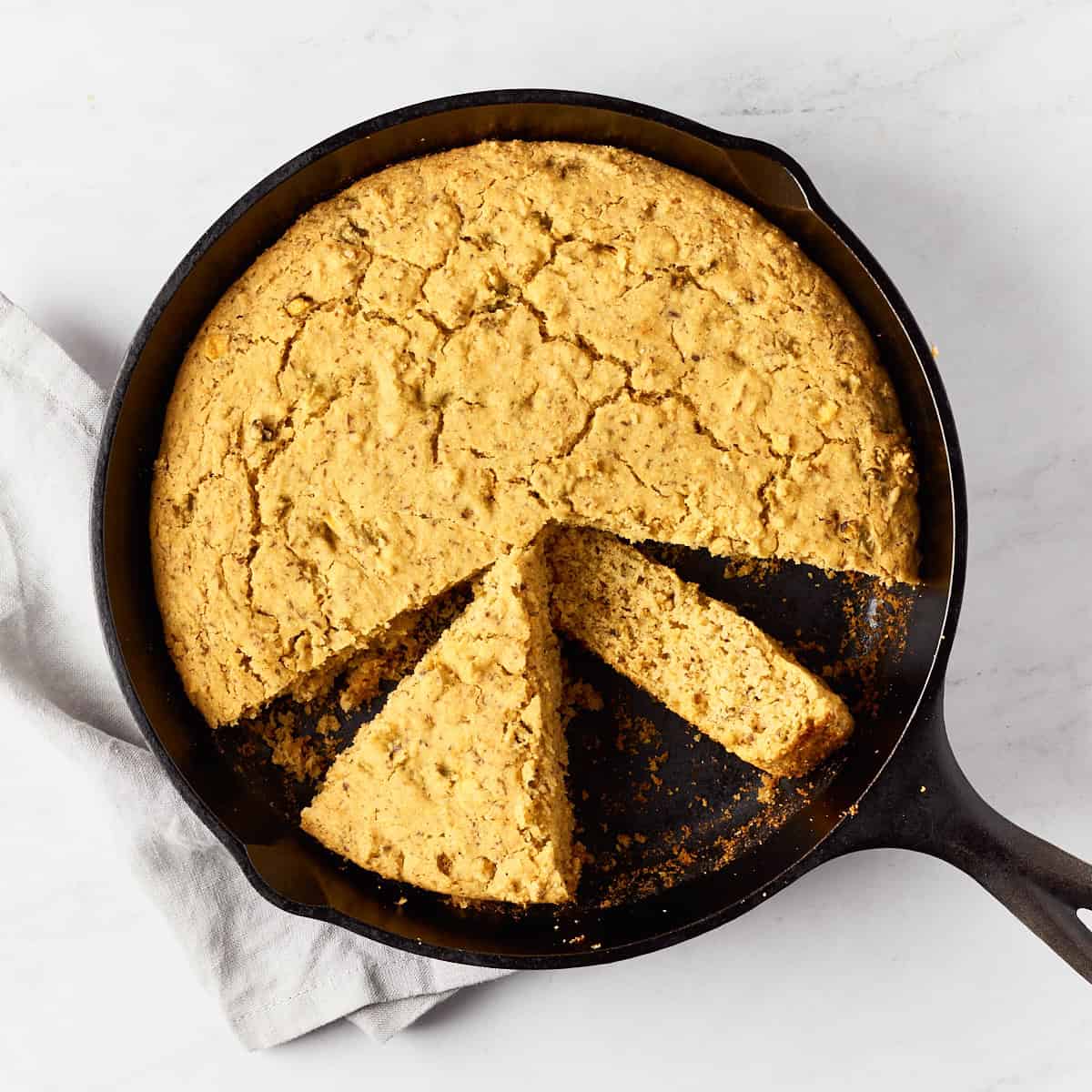 Vegan southwest skillet cornbread in cast iron skillet on marble surface with grey napkin.