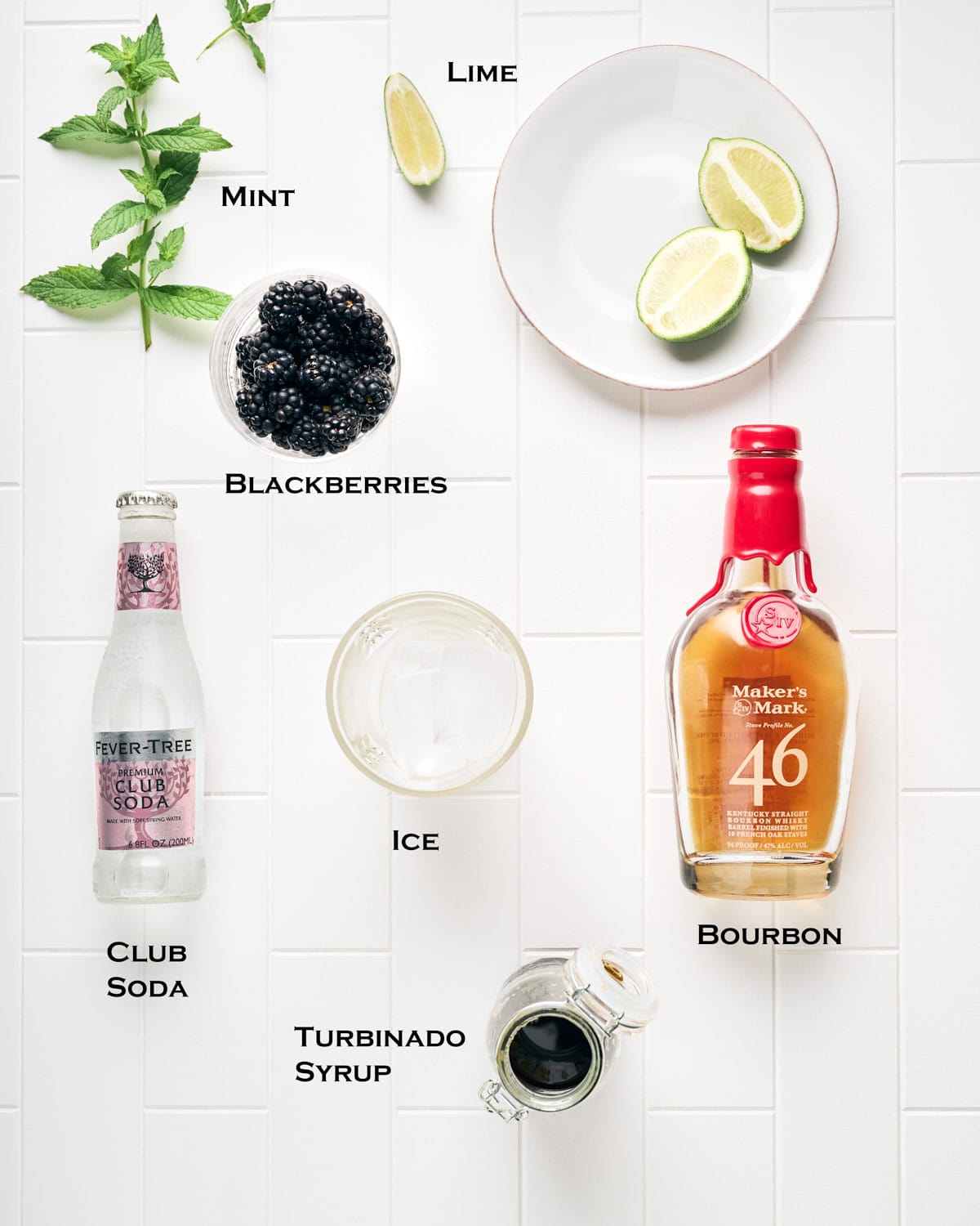 Ingredients to make Blackberry Bourbon Smash on a white tile surface.