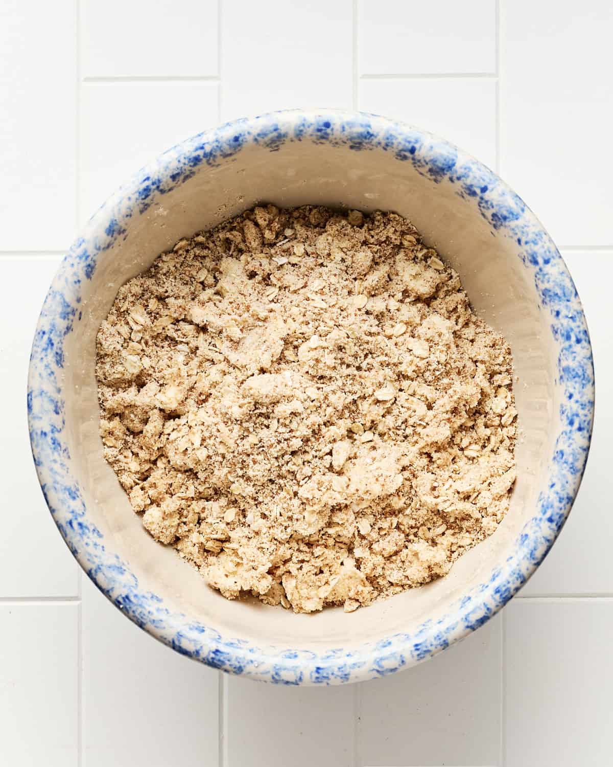 Adding cubed butter and incorporating in the biscuit topping mix to make the topping for the vegan blueberry cobbler.