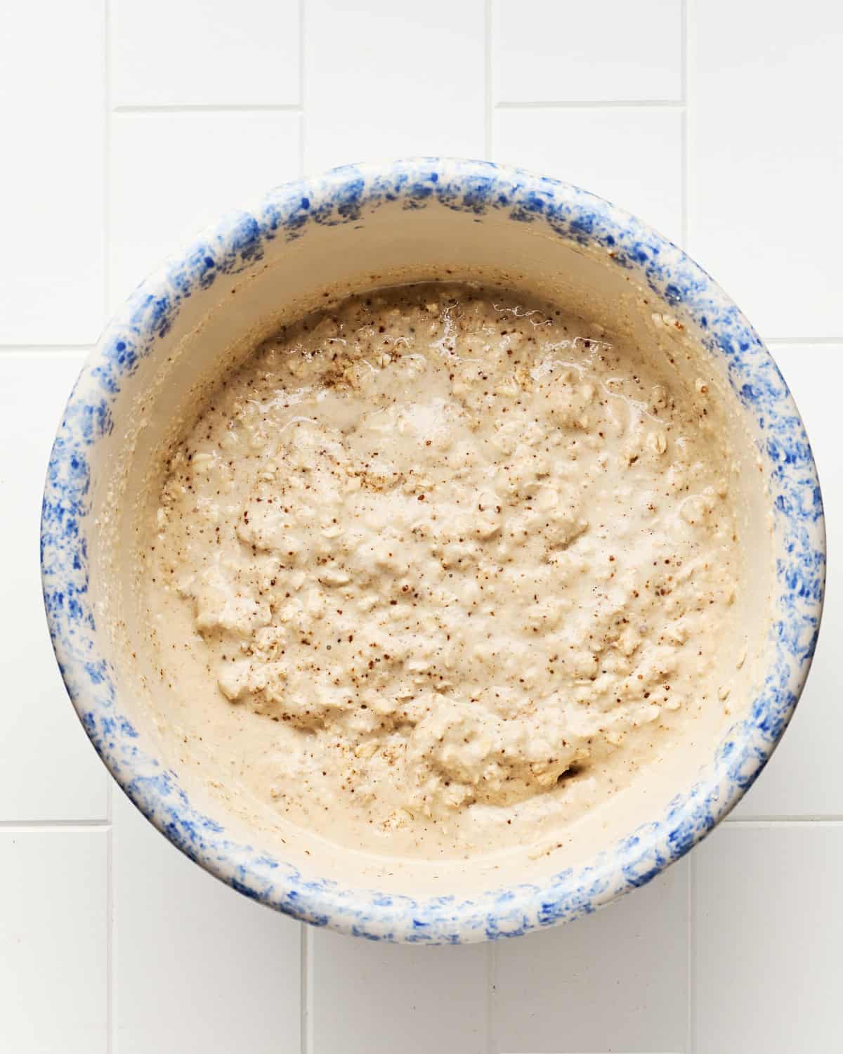 Adding coconut milk to the cobbler topping in a large mixing bowl.