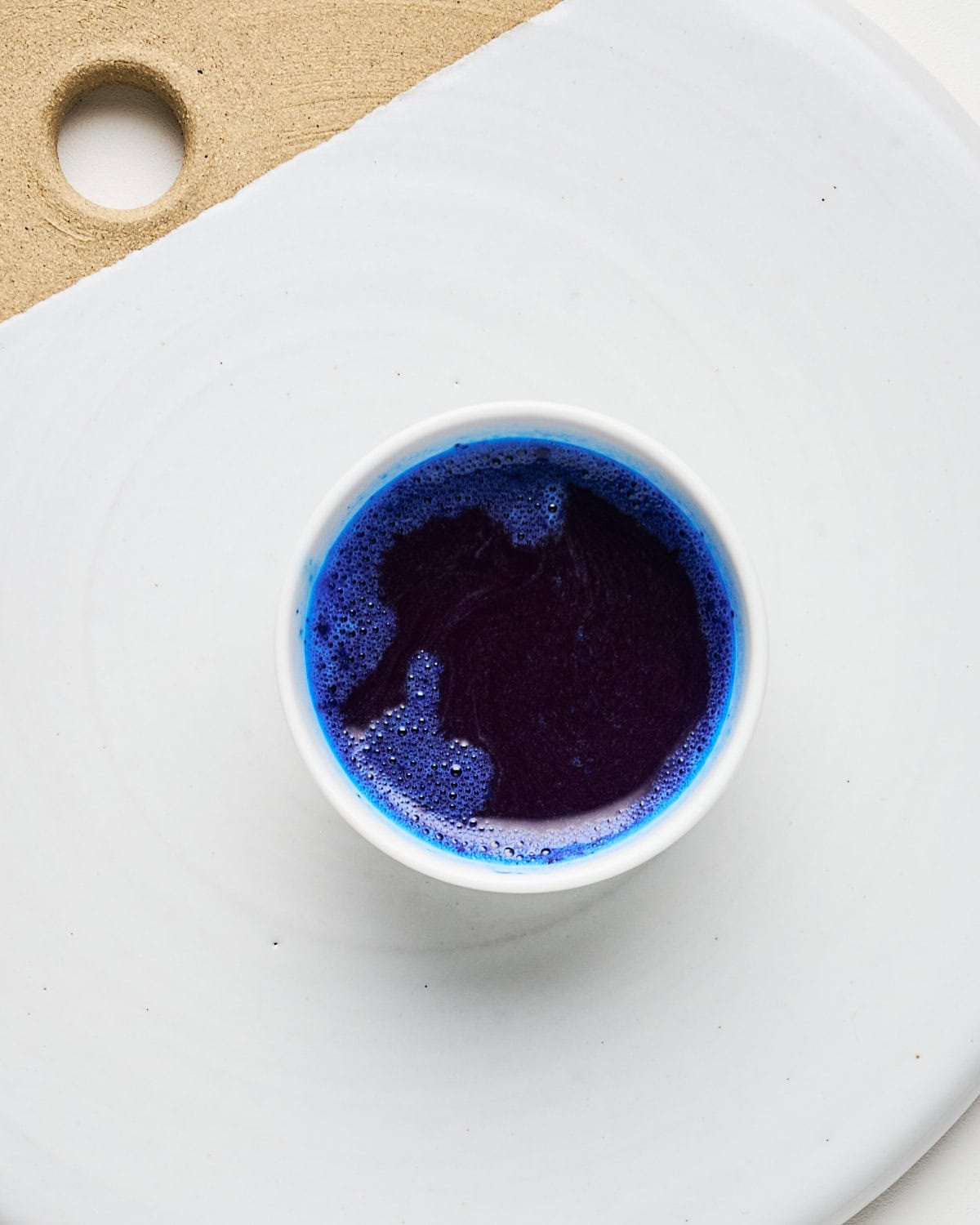 Small bowl of blue spirulina dissolved into coconut water after whisking.