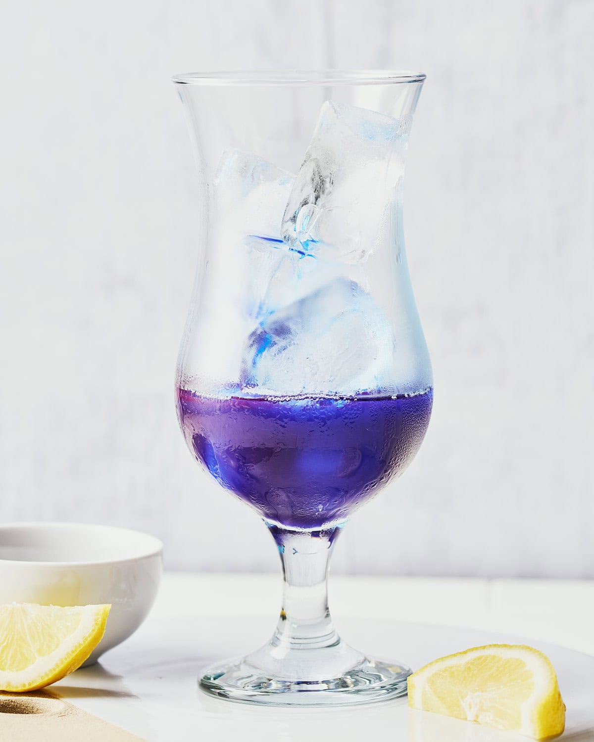 Hurricane glass filled with ice and spirulina and coconut mixture poured over.