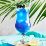 Blue Lagoon Mocktail garnished lemon, cherries, and a straw.