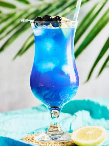 Blue Lagoon Mocktail garnished lemon, cherries, and a straw.