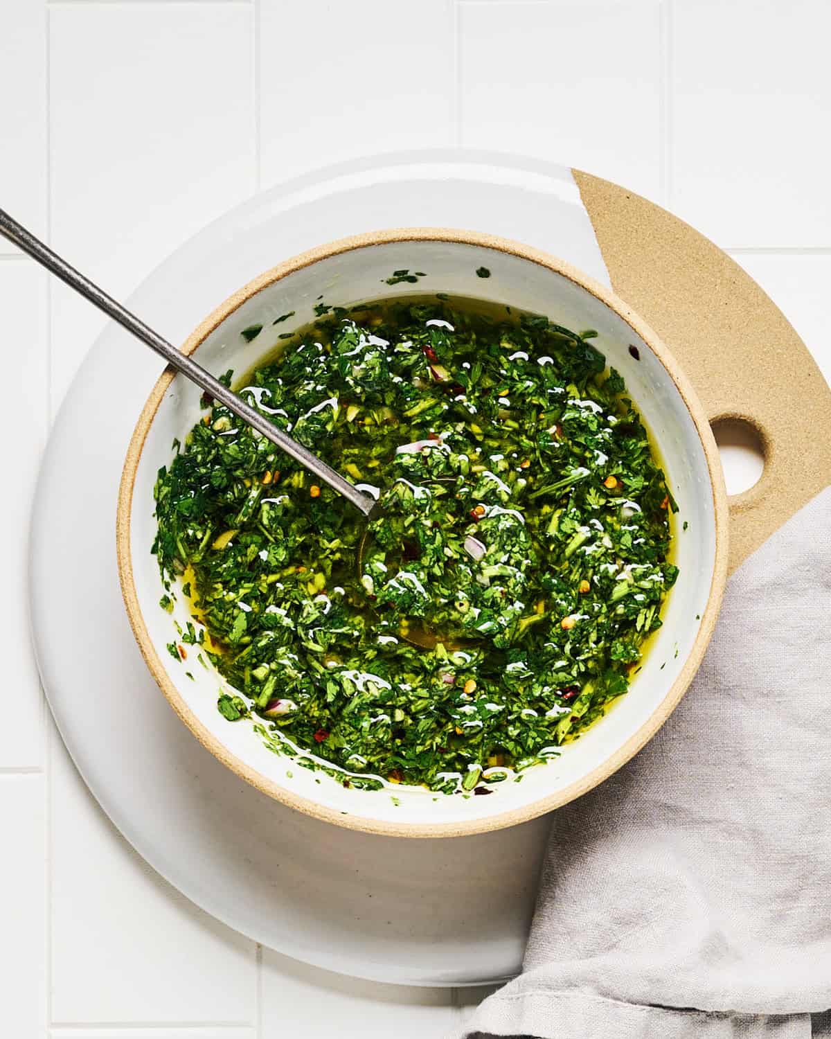 Carrot Top Chimichurri in a bowl with a spoon and napkin nearby.
