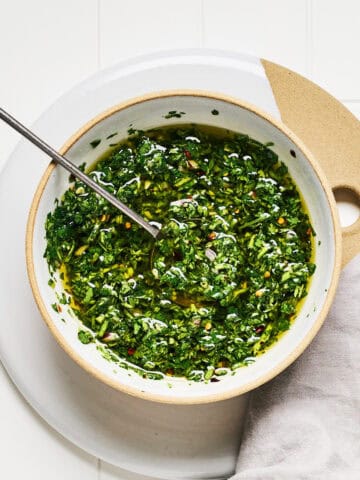Carrot Top Chimichurri in a bowl with a spoon and napkin nearby.