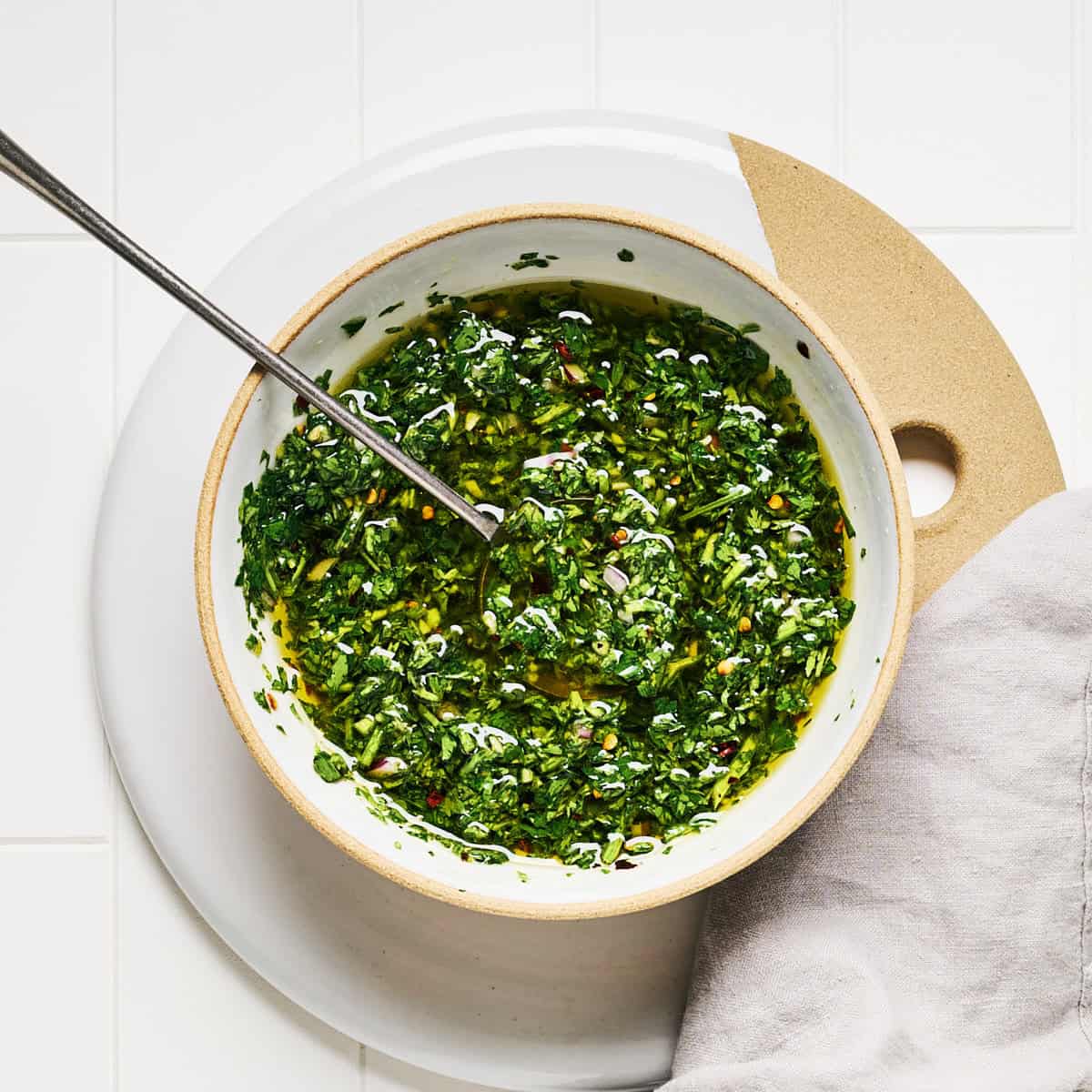 Carrot Top Chimichurri in a bowl with a spoon and napkin nearby.
