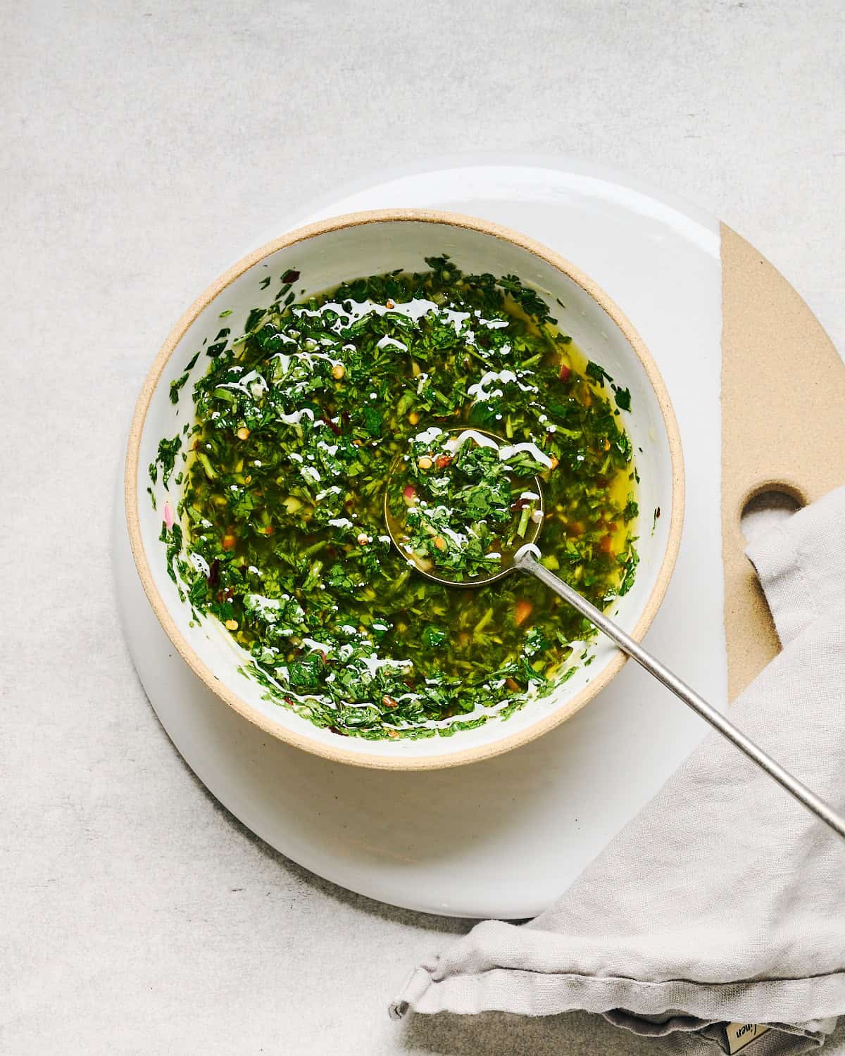 Carrot Top Chimichurri sauce in a bowl with a spoon and a napkin nearby.
