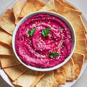 Bowl of Roasted Beet Hummus in a bowl with pita chips.