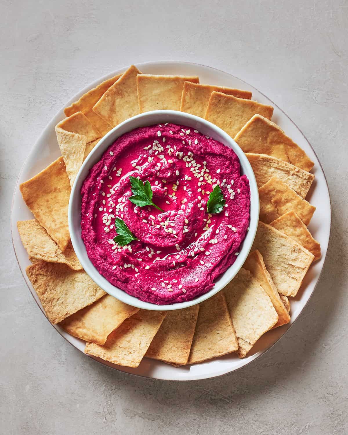 Bowl of Roasted Beet Hummus in a bowl with pita chips.