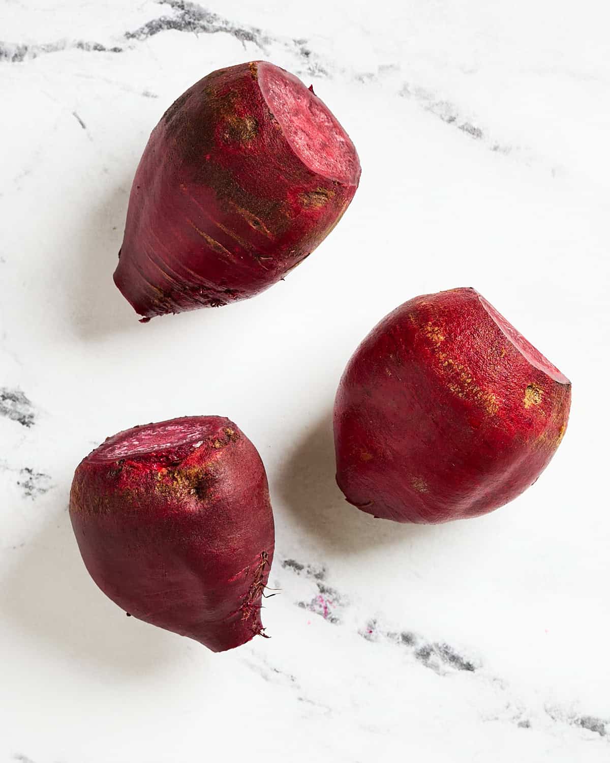 Three scrubbed beets with the ends cut off on both sides.