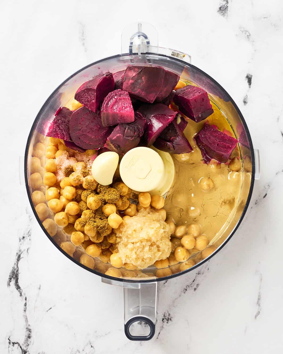 Ingredients placed in food processor bowl to make roasted beet hummus.
