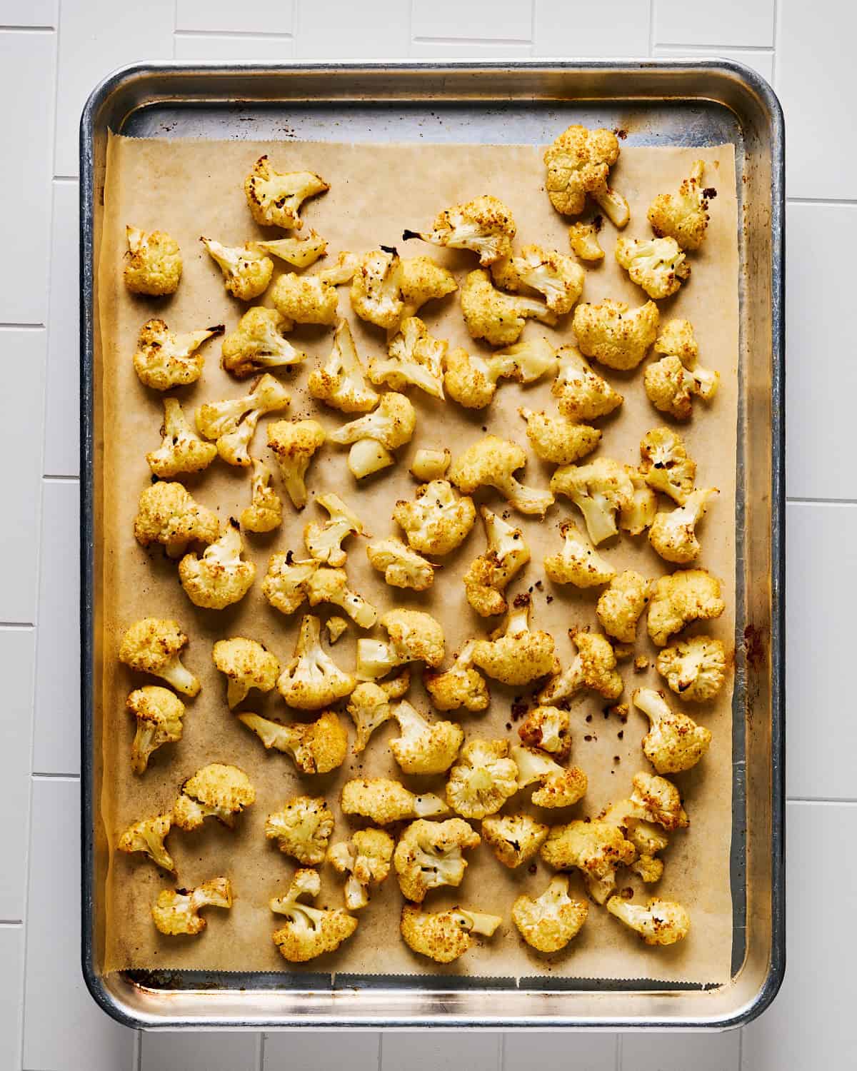 Roasted cauliflower florets on a rimmed baking sheet.