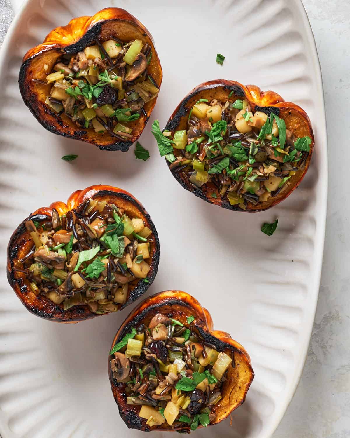 Carnival squash stuffed with wild rice leek stuffing on a platter.