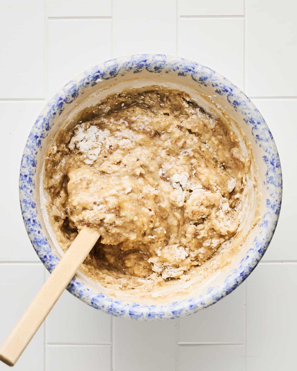 Mixing vegan banana bread batter in a bowl with a spatula.