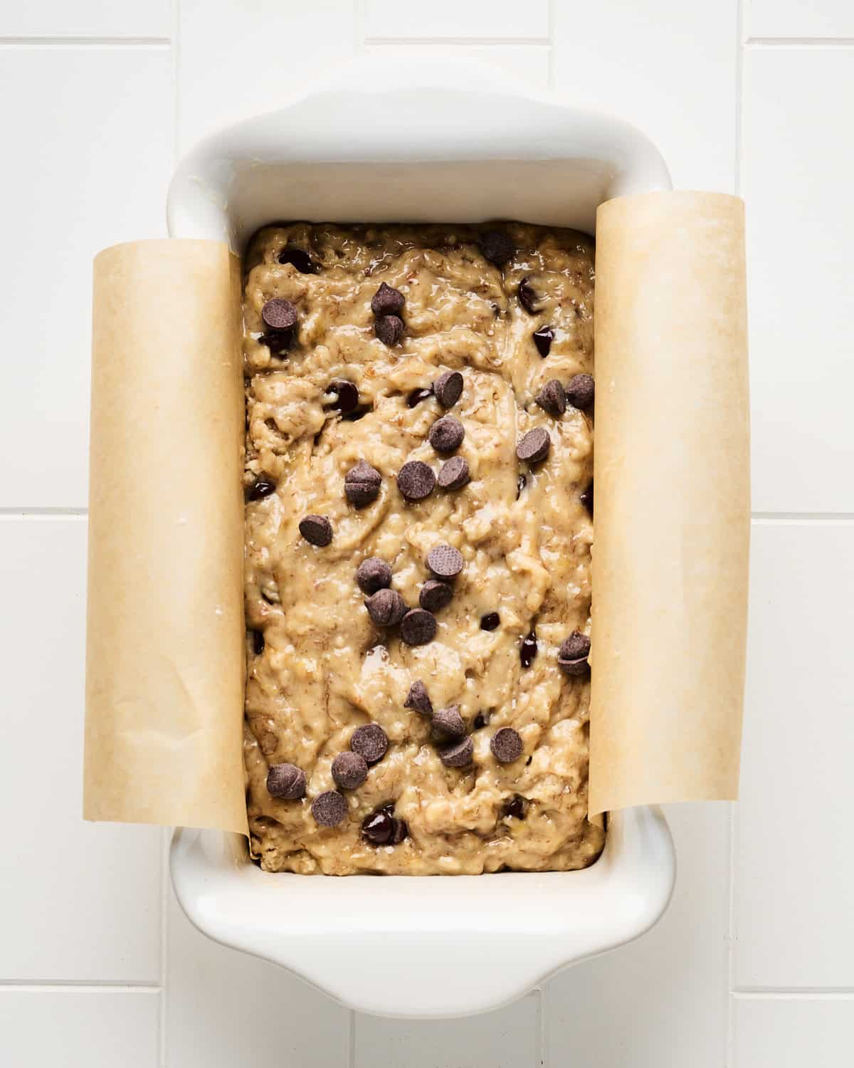Vegan banana bread batter with chocolate chips in a baking dish.