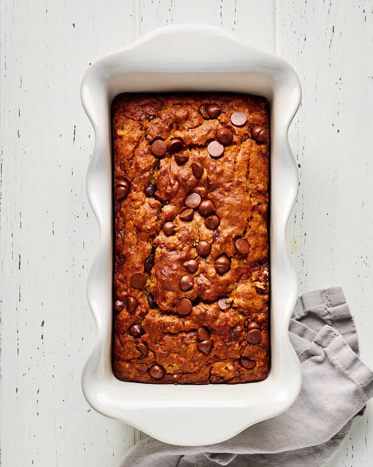 Loaf of vegan banana bread with chocolate chips in a loaf baking dish.