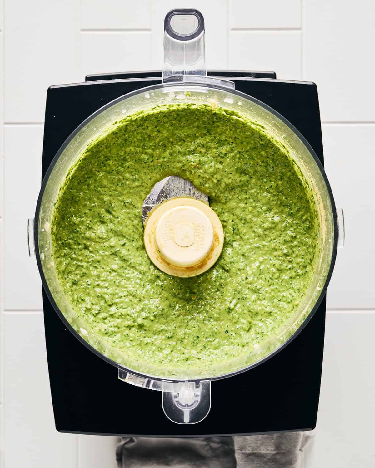 Blended vegan basil pesto with pine nuts in the food processor bowl.