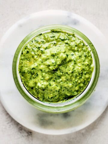 Small glass jar of vegan basil pesto with pine nuts.
