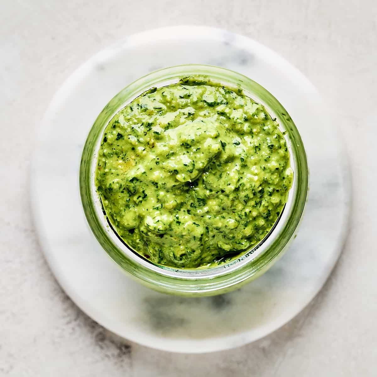 Small glass jar of vegan basil pesto with pine nuts.