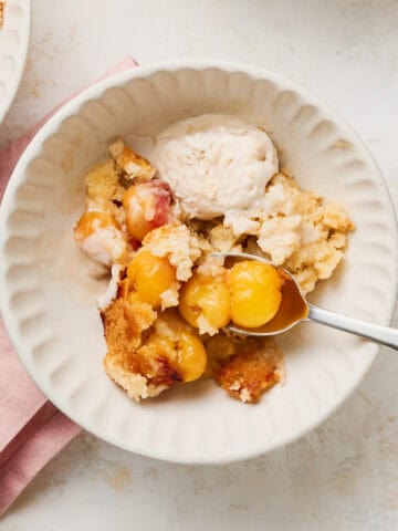 A serving of Vegan Cherry Cobbler in a bowl with a spoon and a napkin.