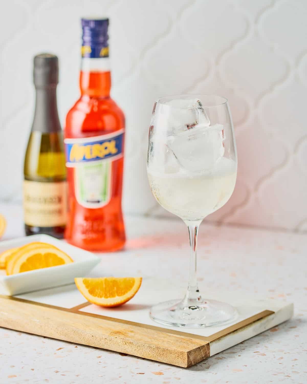 Ice in a white wine glass with Prosecco poured on top.