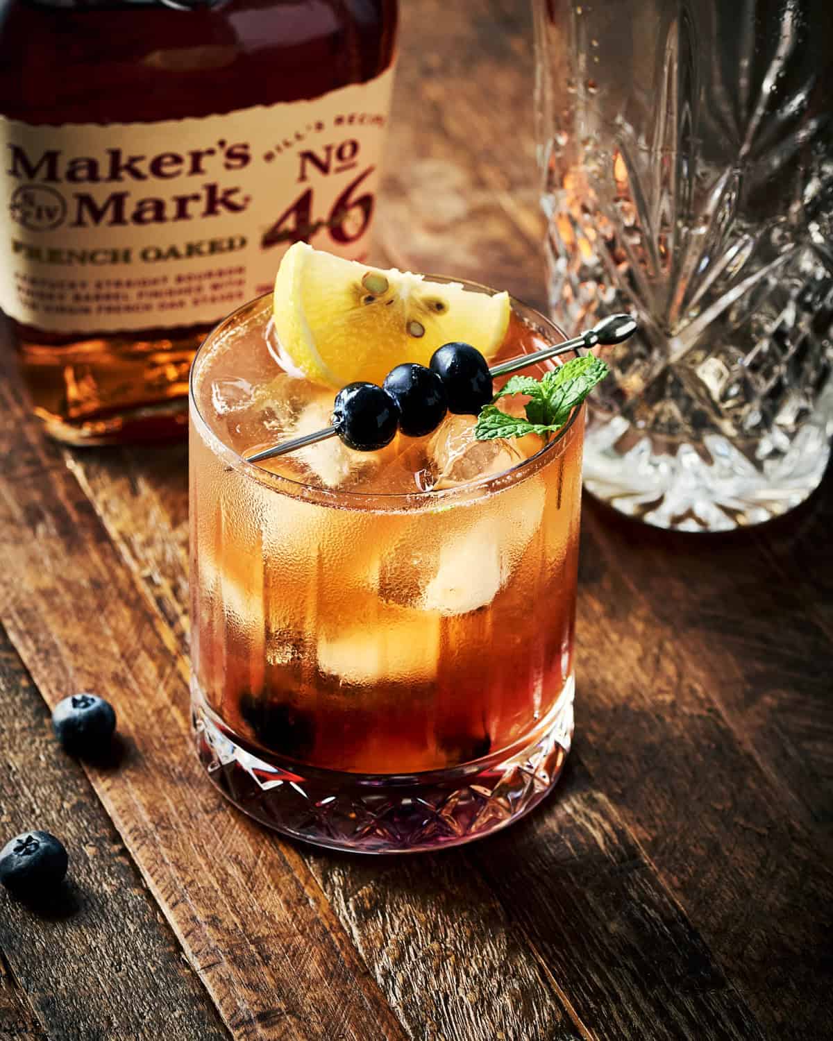 Blueberry Bourbon Smash with a mint garnish and cocktail stick of blueberries.
