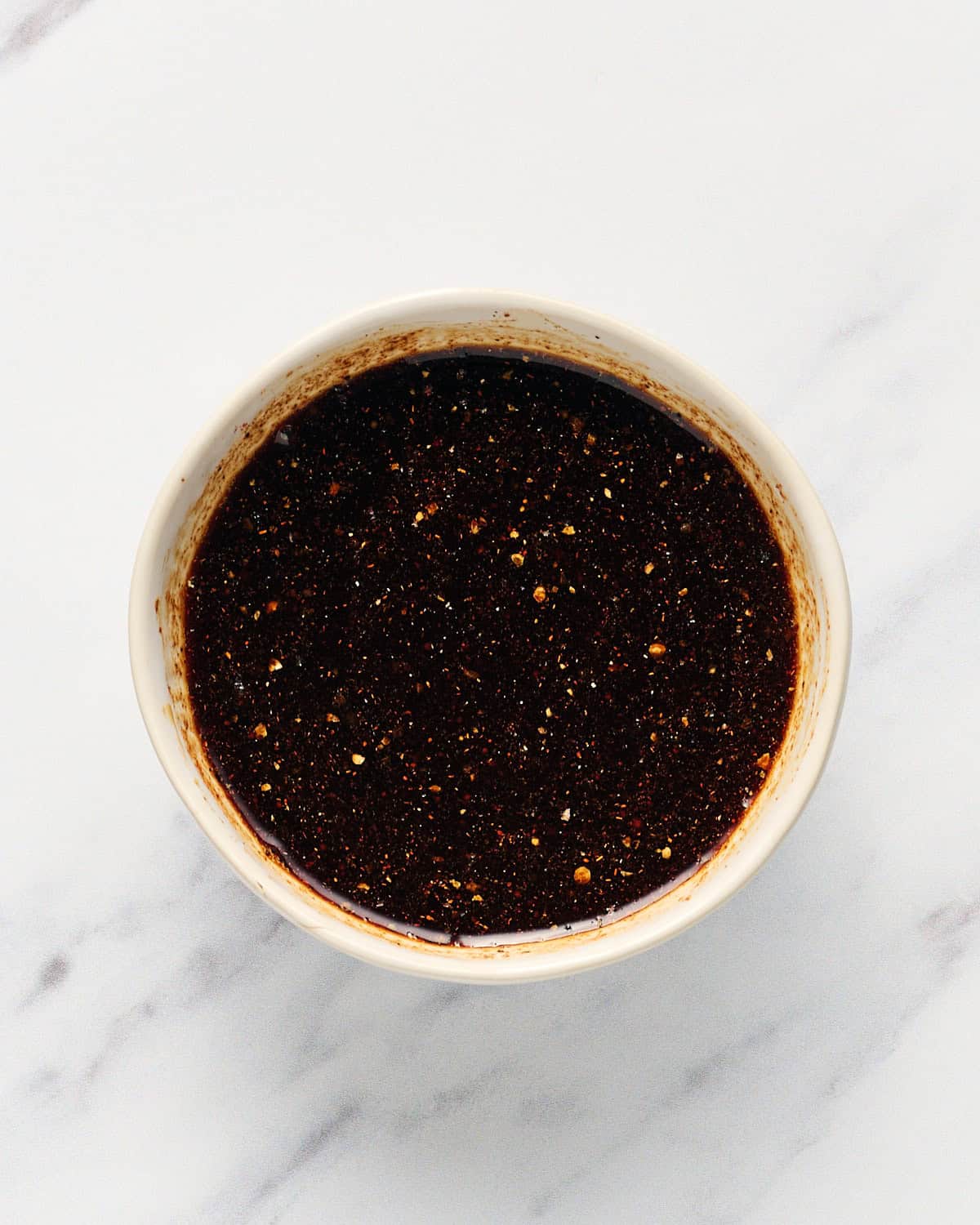 Liquid and dry ingredients mixed in a small bowl to make coconut bacon seasoning.