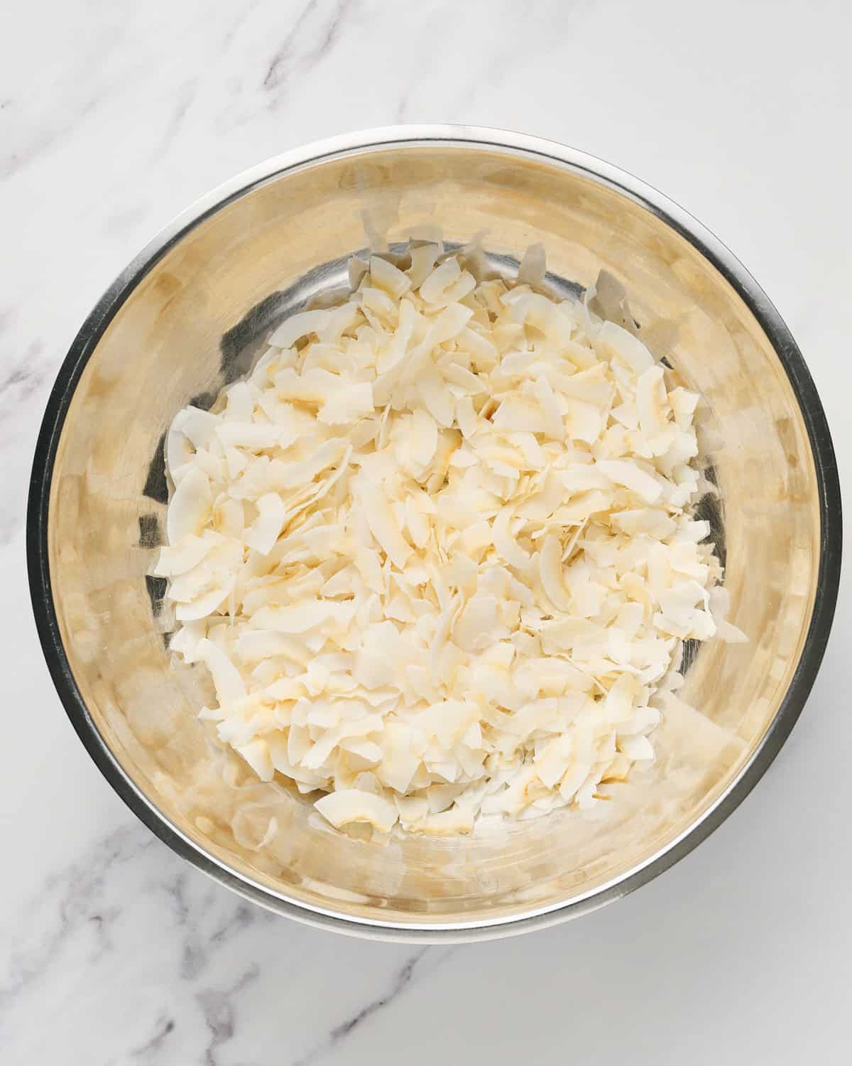 Large unsweetened dried coconut flakes in a bowl.