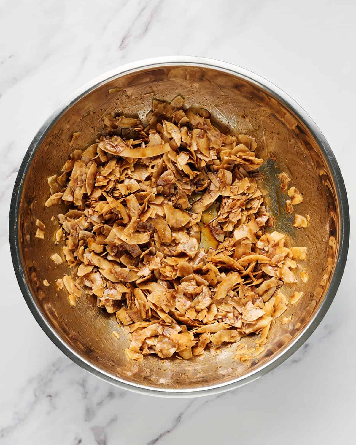 Mixed wet seasoning into dried large coconut flakes in a large bowl.
