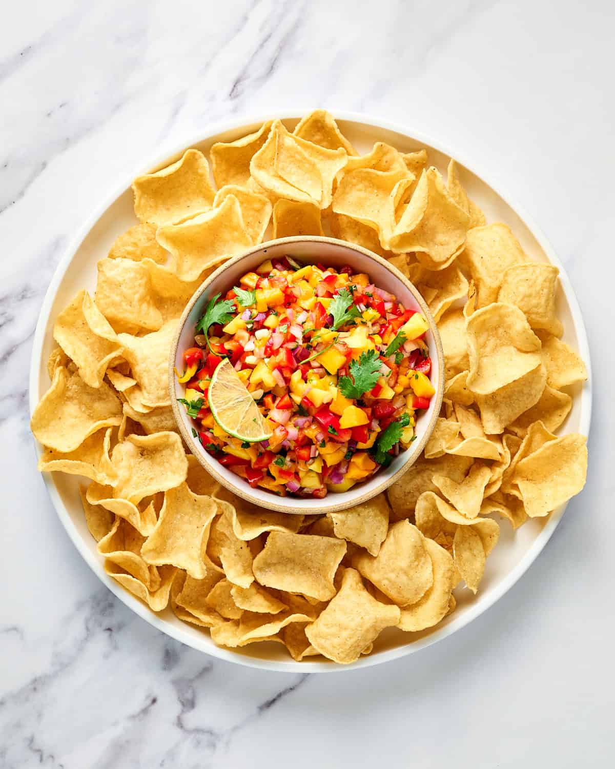 Bowl of Mango Habanero Salsa with tortilla chips on a platter.