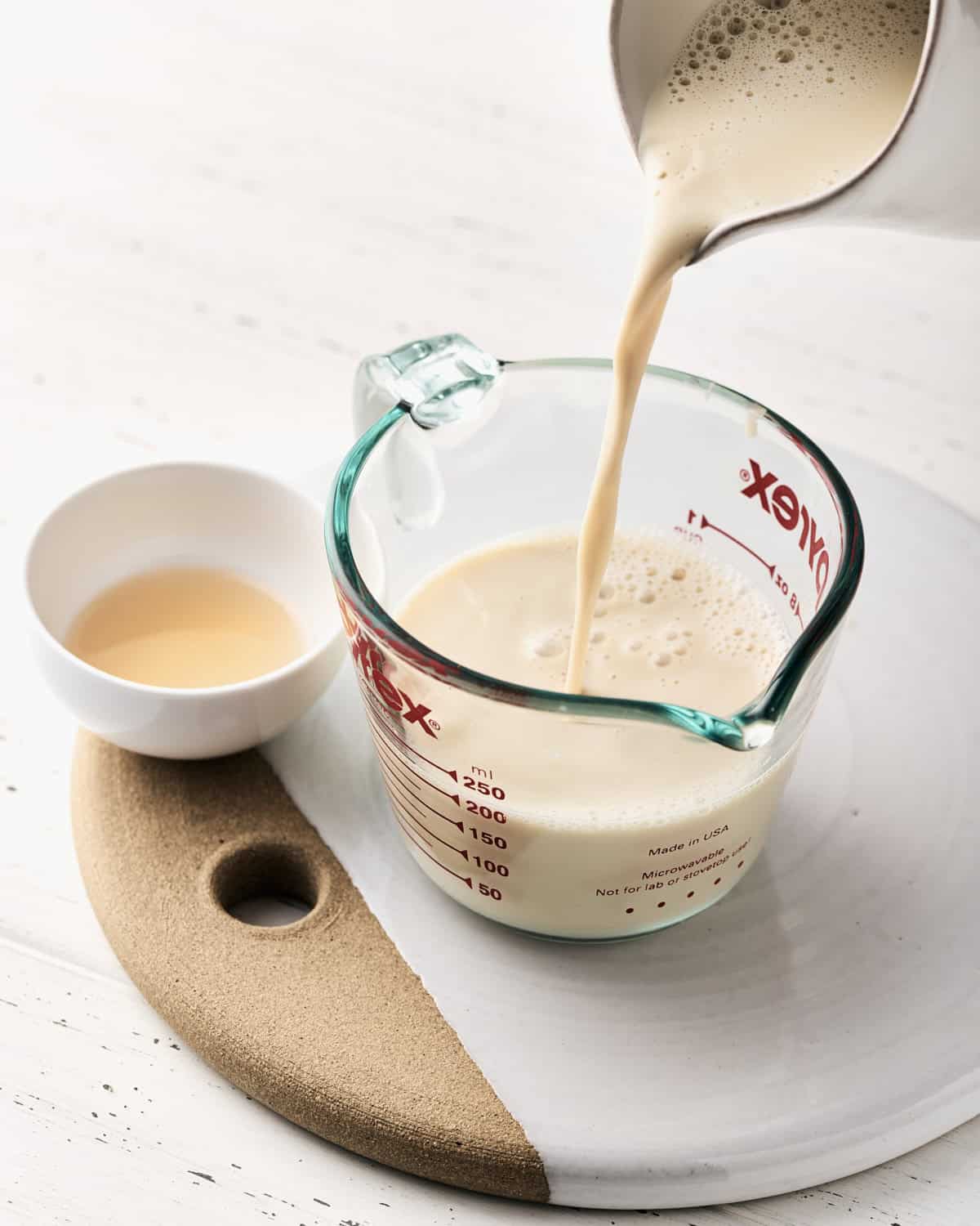 Pouring soy milk in a glass measuring cup.