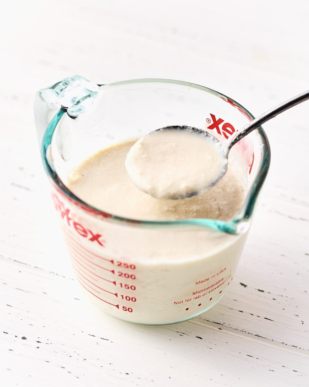 Vegan Buttermilk in a measuring cup with a spoon.