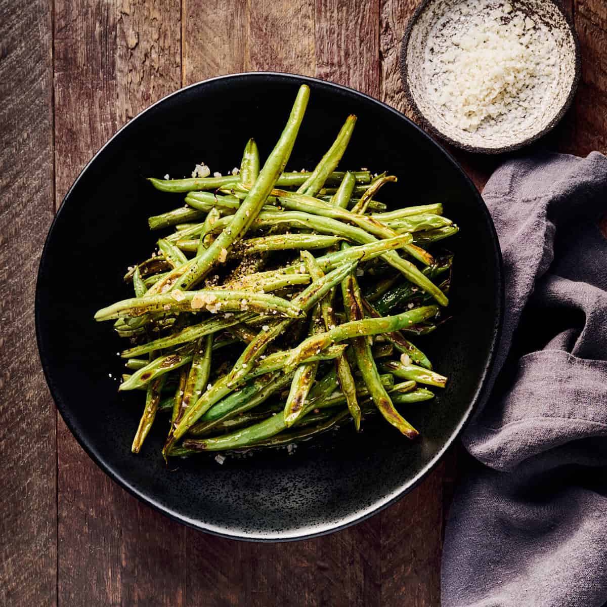 Roasted green beans with garlic, salt, and pepper in a serving bowl.