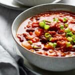 Bowl of vegan pumpkin chili garnished with sliced green onion.