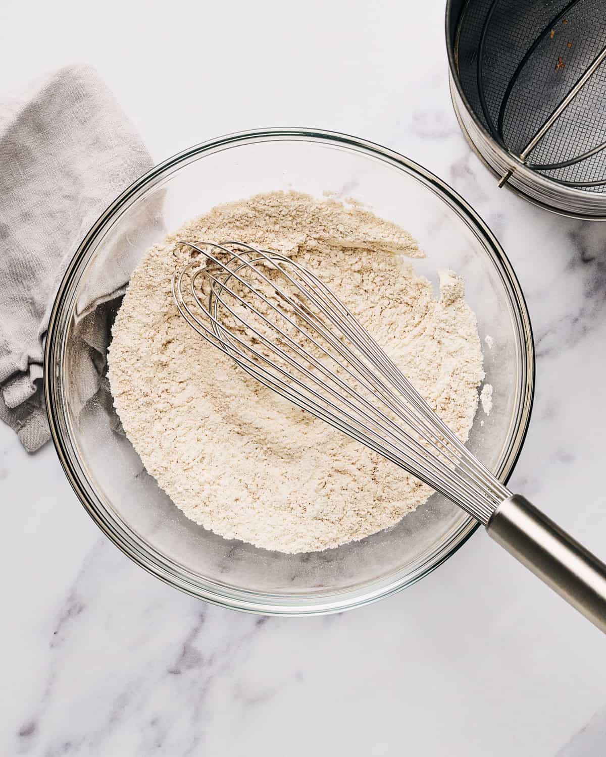 Dry ingredients in mixing bowl with a whisk to make vegan oatmeal raisin cookies.
