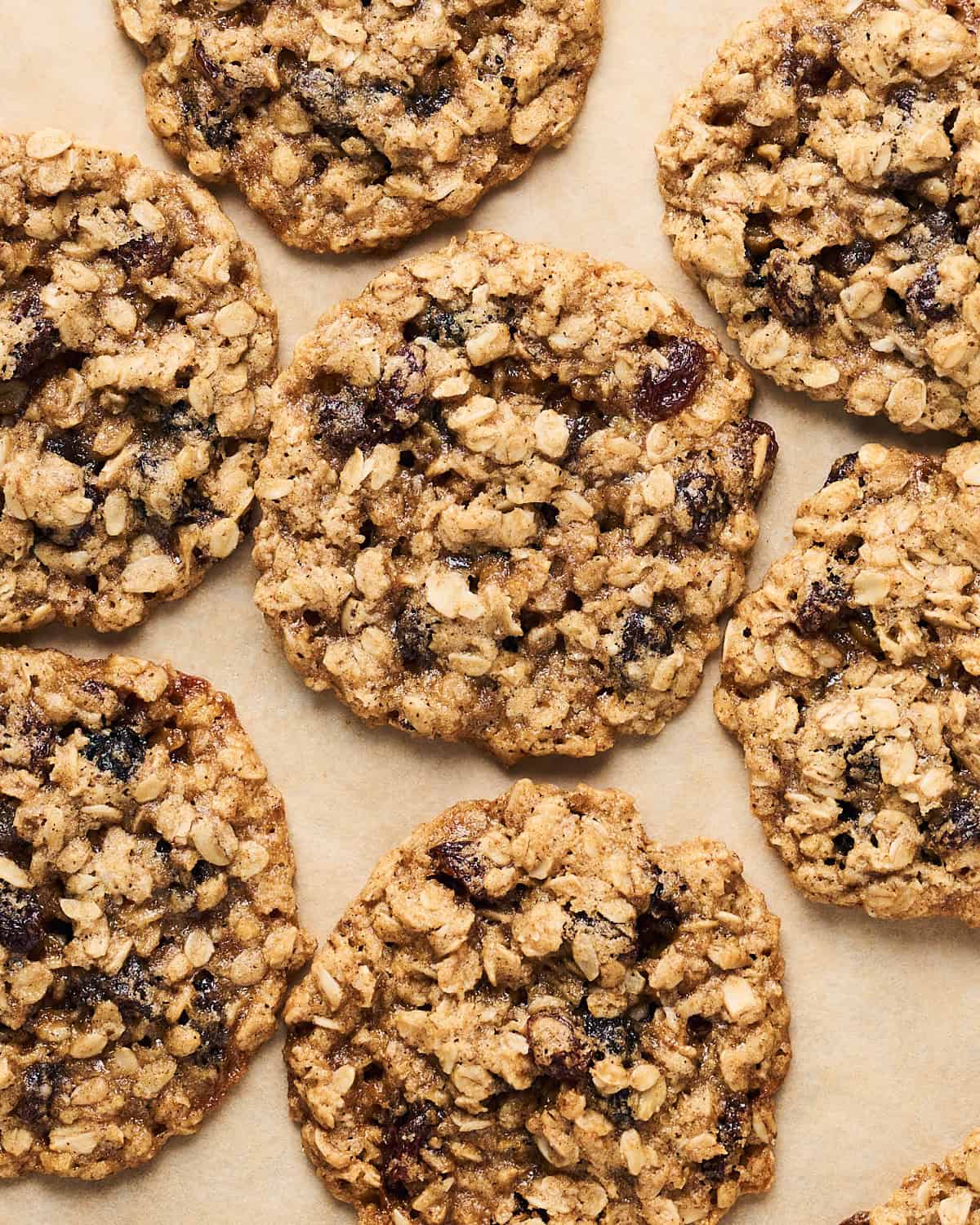 Vegan oatmeal raisin cookies in a group on parchment paper.