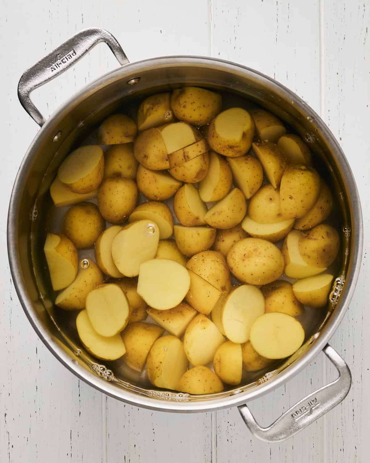 Halved baby Yukon gold potatoes in a large pot of water ready to boil.